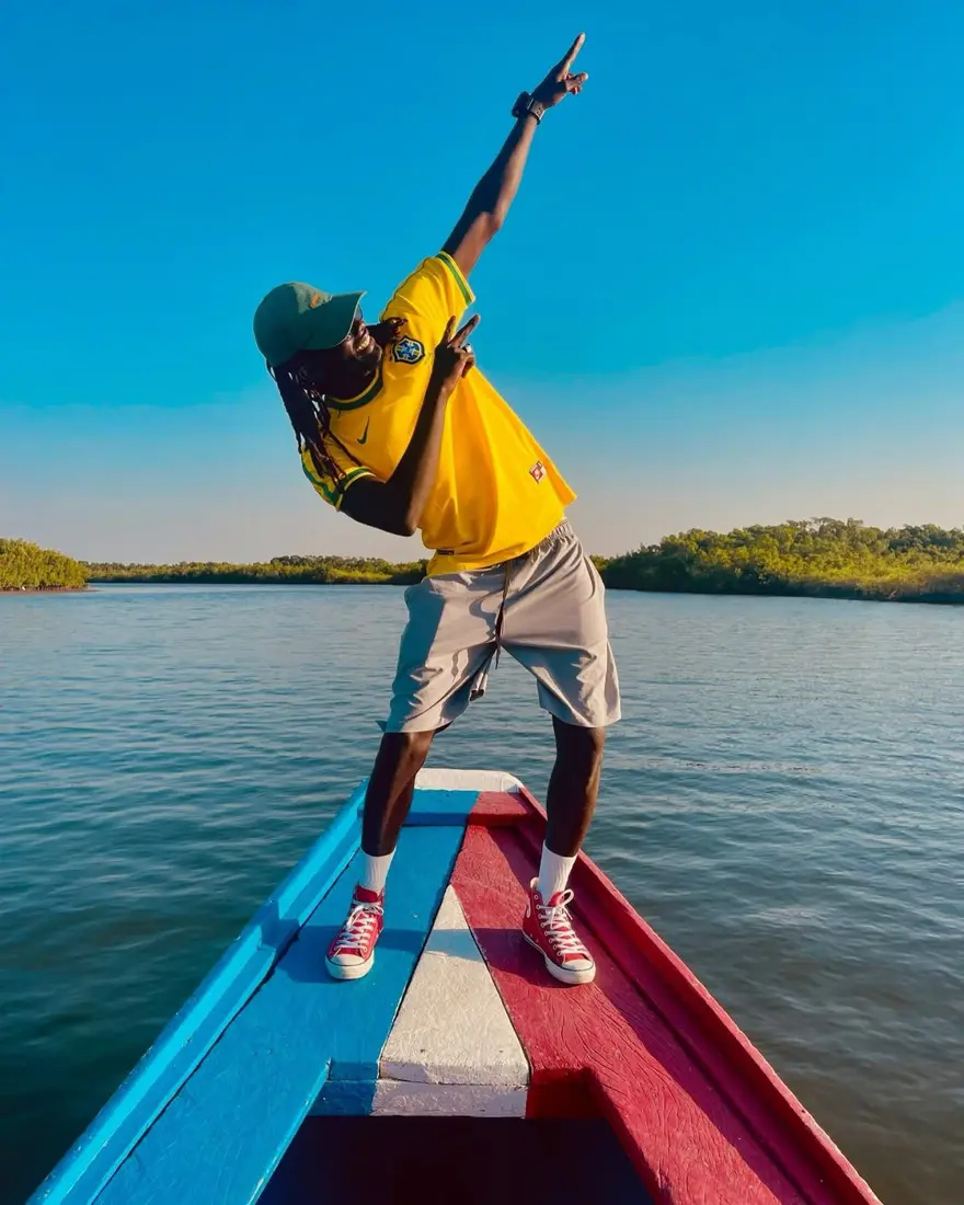 Voyageur debout à la proue d'une pirogue sur un bolong bordé de mangroves